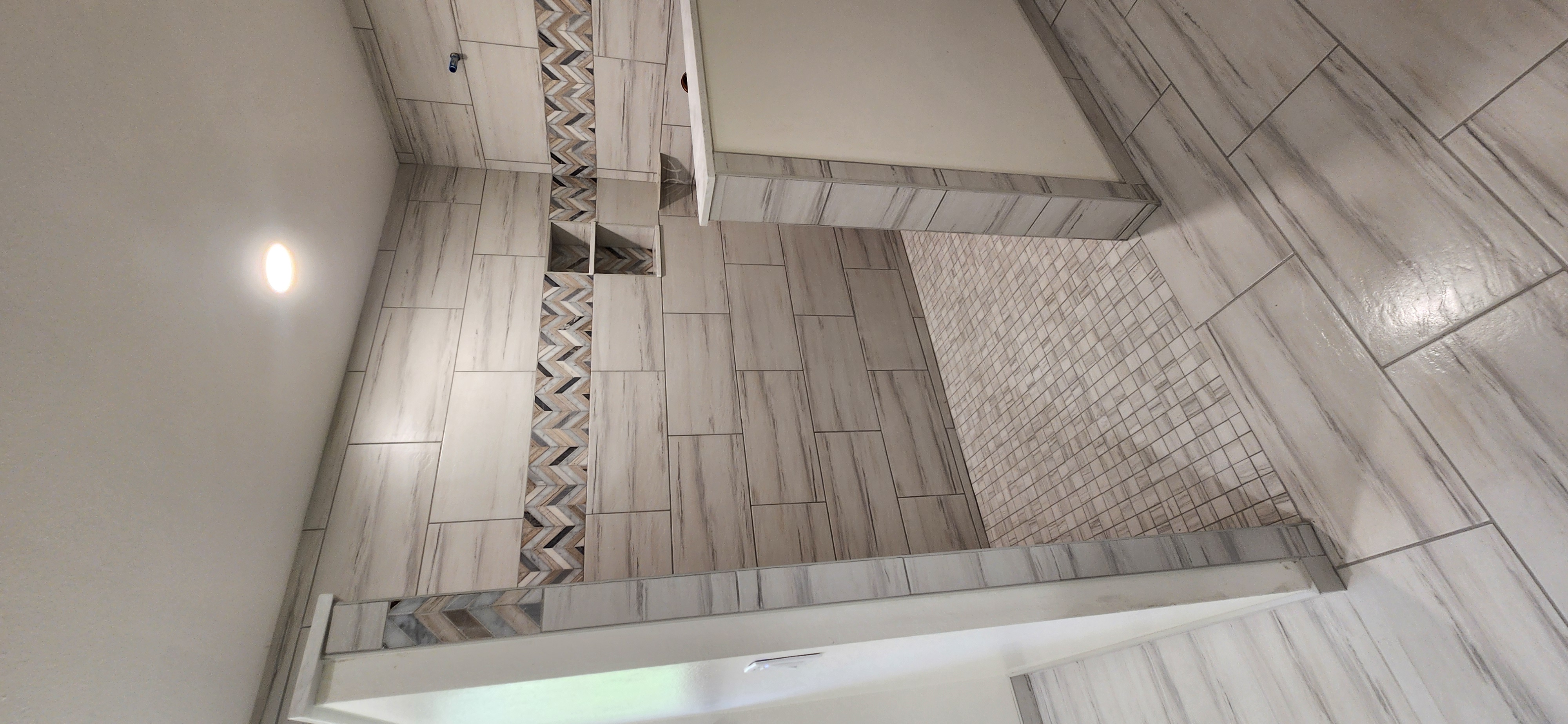 Walk-in shower with tile walls and mosaic pan